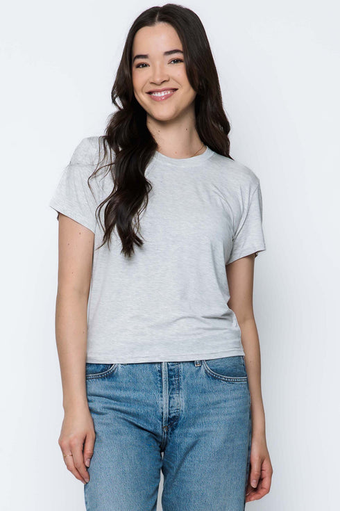 Woman wearing a gray t-shirt and blue jeans against a white background