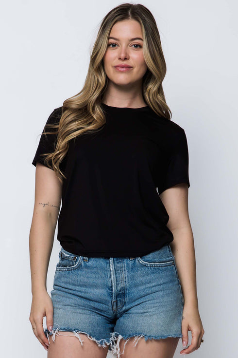 Woman wearing a black t-shirt and denim shorts against a white background