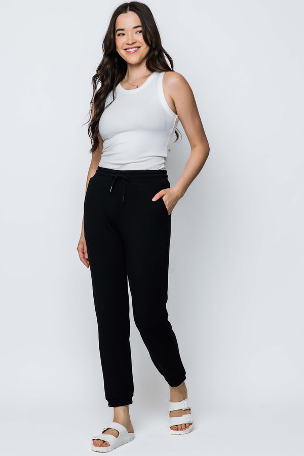 Woman wearing a white tank top and black luxe fleece sweatpants