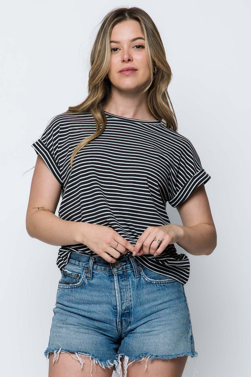 Woman wearing a black and white striped shirt and denim shorts on a white background