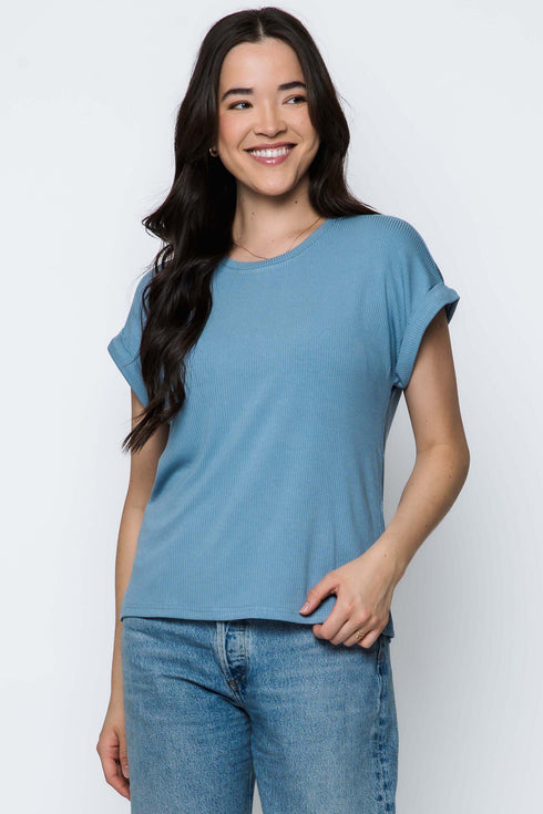 Woman wearing a blue t-shirt and jeans against a white background