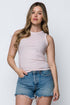 Woman wearing a pink sleeveless top and denim shorts against a white background