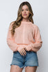 Woman wearing a pink knitted sweater and denim shorts on a white background