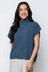 Woman wearing a blue knitted sleeveless sweater against a white background