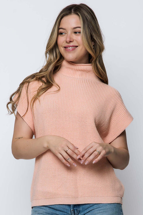 Woman wearing a light pink sweater against a white background