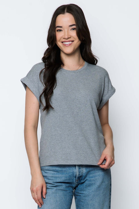 Woman wearing a gray t-shirt and blue jeans against a white background