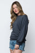 Woman wearing a dark gray long-sleeve top and denim shorts on a white background