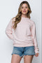 Woman wearing a light pink sweater and denim shorts on a white background
