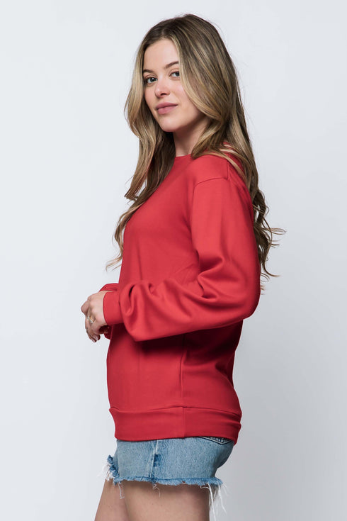 Woman wearing a red luxe fleece, crew neck, long sleeve sweatshirt