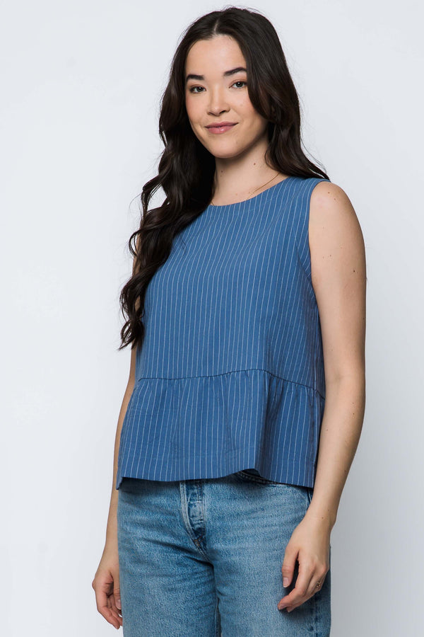 Woman wearing a blue sleeveless top and jeans on a white background