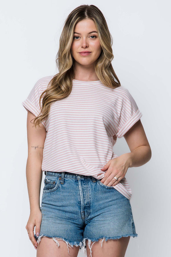 Woman wearing a light pink striped t-shirt and denim shorts on a white background