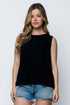 Woman wearing a black sleeveless peplum top and denim shorts on a white background