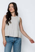 Woman wearing a natural linen sleeveless peplum top and jeans on a white background