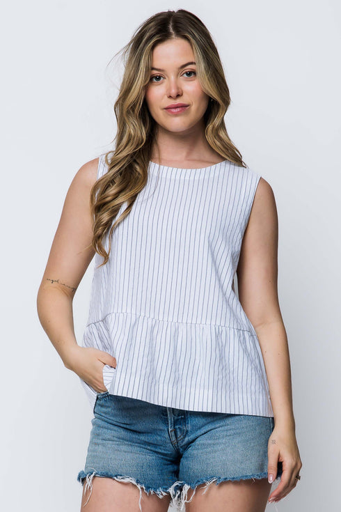 Woman wearing a white stripe peplum sleeveless top and denim shorts on a white background
