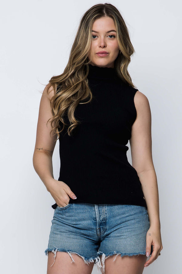 Woman wearing a black sleeveless top and denim shorts on a white background