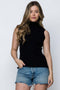 Woman wearing a black sleeveless top and denim shorts on a white background