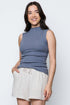 Woman wearing a blue sleeveless top and white shorts on a light gray background