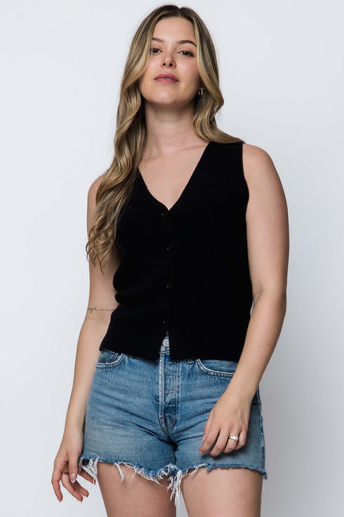 Woman wearing a black sleeveless top and denim shorts on a white background