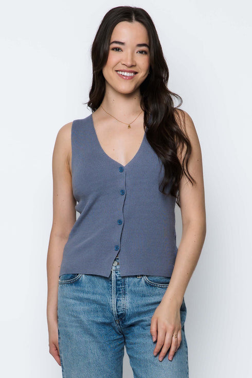 Woman wearing a blue sleeveless top and jeans on a white background