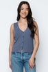 Woman wearing a blue sleeveless top and jeans on a white background