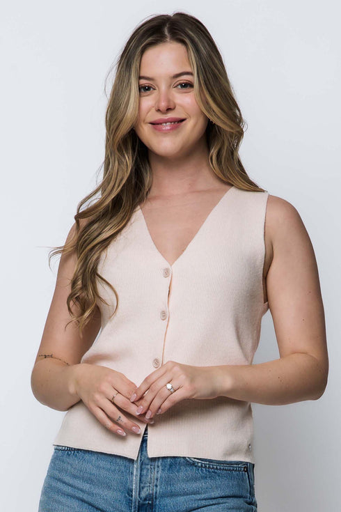 Woman wearing a light pink sleeveless top and blue jeans against a white background