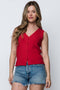 Woman wearing a red sleeveless top and denim shorts against a white background