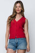 Woman wearing a red sleeveless top and denim shorts against a white background