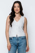 Woman wearing a white sleeveless top and blue jeans against a plain background