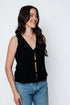 Woman wearing a black sleeveless top and blue jeans against a white background