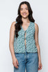 Woman wearing a floral sleeveless top and jeans against a white background