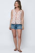 Woman wearing a floral sleeveless top and denim shorts on a white background