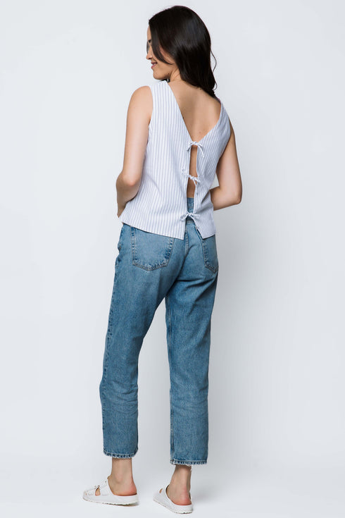 Woman wearing a white sleeveless top and blue jeans on a white background