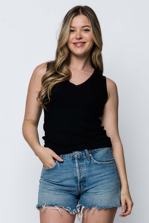 Woman wearing a black tank top and denim shorts on a white background