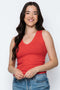 Woman wearing a red tank top and blue jeans against a white background
