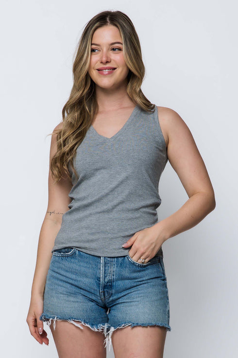 Woman wearing a gray tank top and denim shorts against a white background