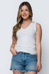 Woman wearing a white tank top and denim shorts on a plain background