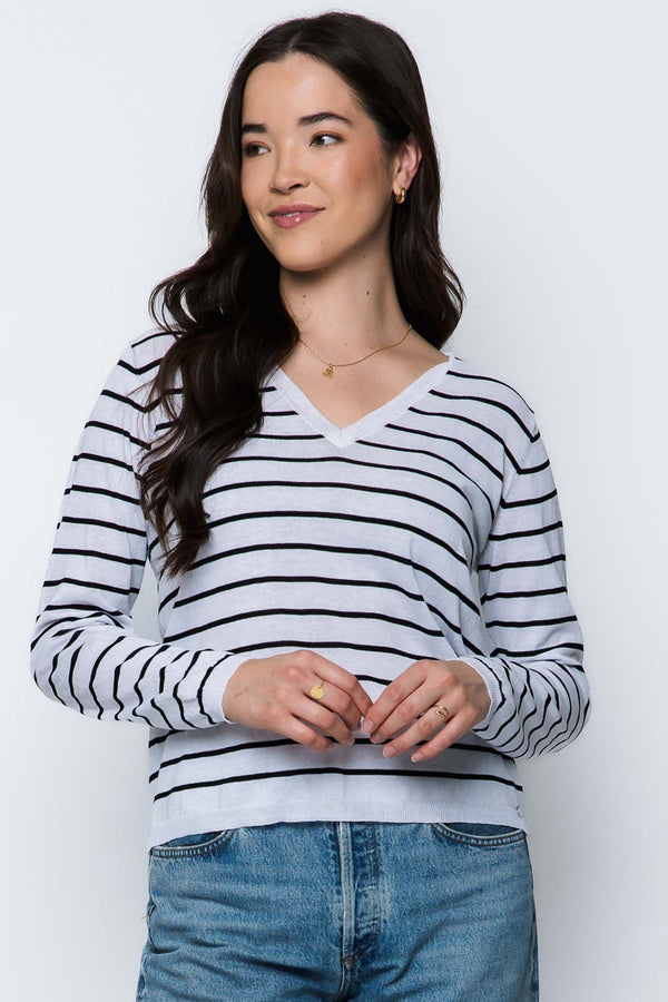 Woman wearing a striped sweater and jeans against a white background