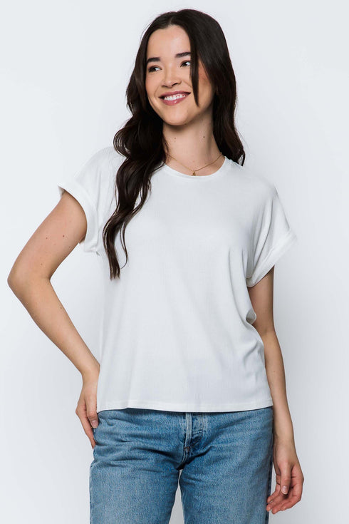 Woman wearing a white t-shirt and blue jeans against a plain background